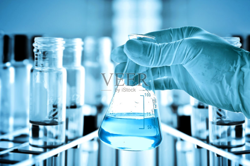 科学家手里拿着烧瓶，架子上放着试管正版图片素材
