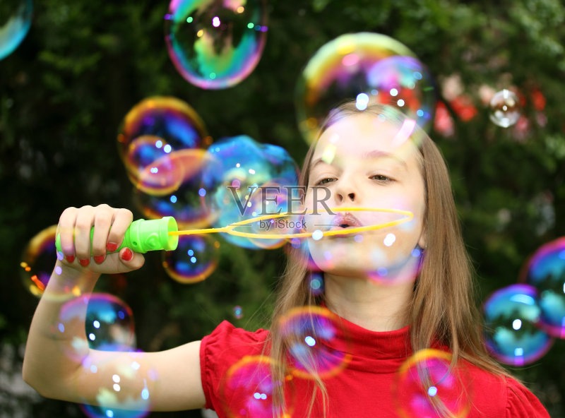 美丽的年轻女孩吹肥皂泡。正版图片素材
