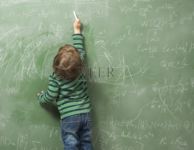 小男孩在绿色的黑板上写字正版图片素材