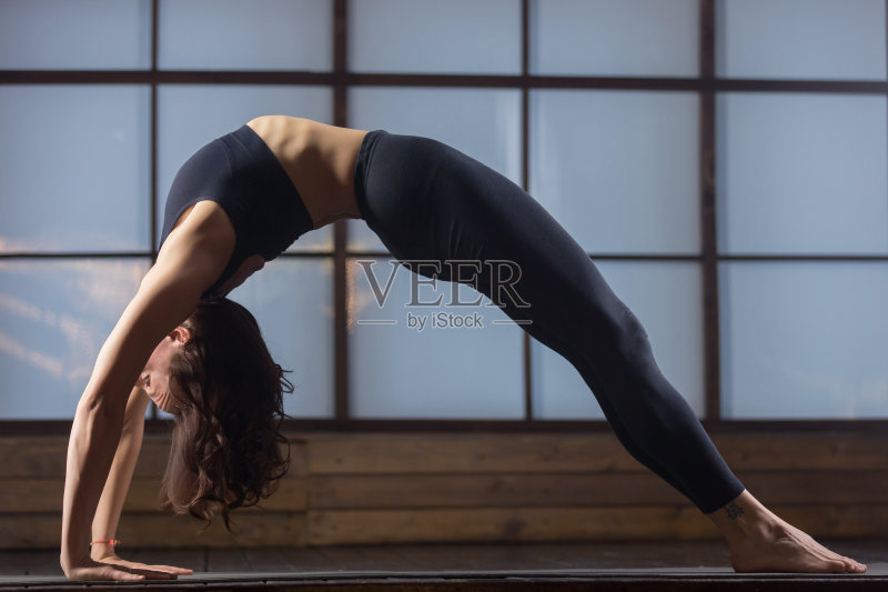年轻迷人的女人在Urdhva Dhanurasana姿势，工作室晚上正版图片素材