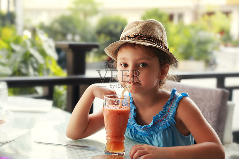 有趣的小女孩在时尚帽子喝冰沙果汁正版图片素材
