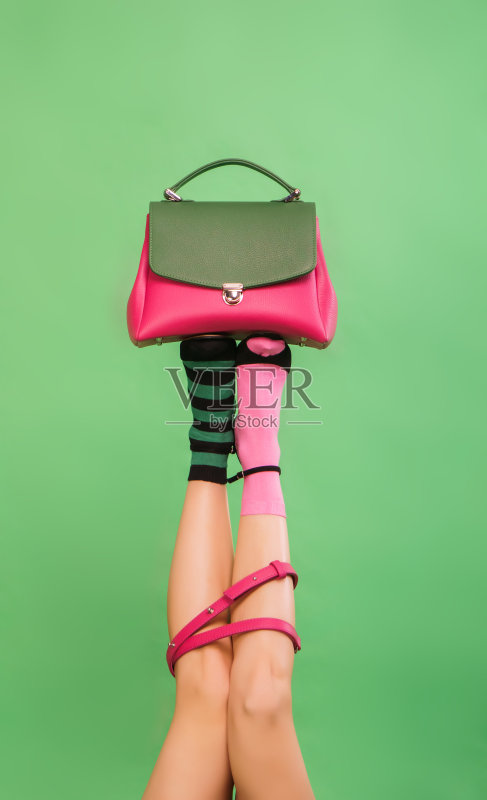 女人的腿拿着手提包在一个绿色的背景正版图片素材