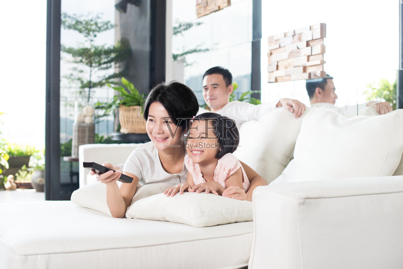 年轻的亚洲家庭在家里看电视。正版图片素材