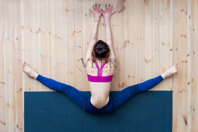 在健身房的伸展课上，年轻女孩表演广角坐姿前屈或上仰体位正版图片素材