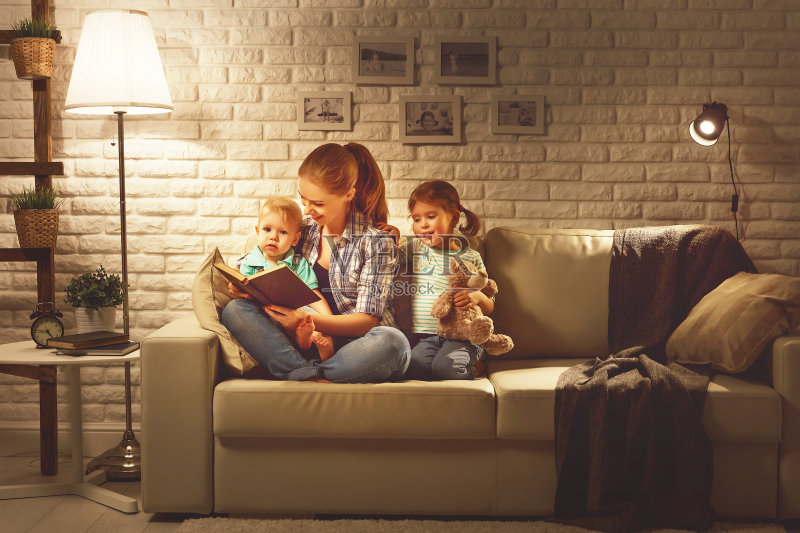 家人睡觉前，妈妈在晚上给孩子们读关于灯的书正版图片素材