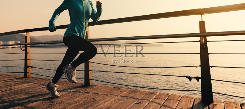 年轻的健身妇女跑步在日出的海滨木板路正版图片素材