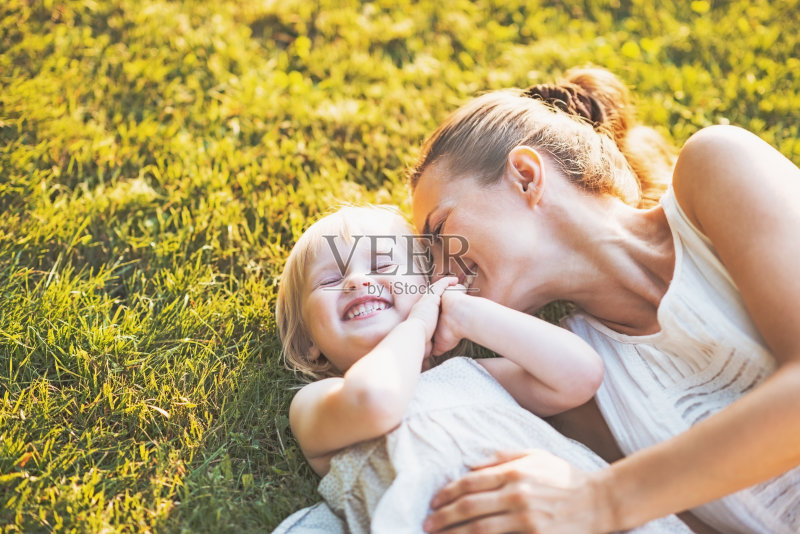 快乐的母亲和婴儿躺在草地上正版图片素材