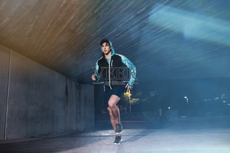 一位健康的年轻人晚上在城里慢跑正版图片素材