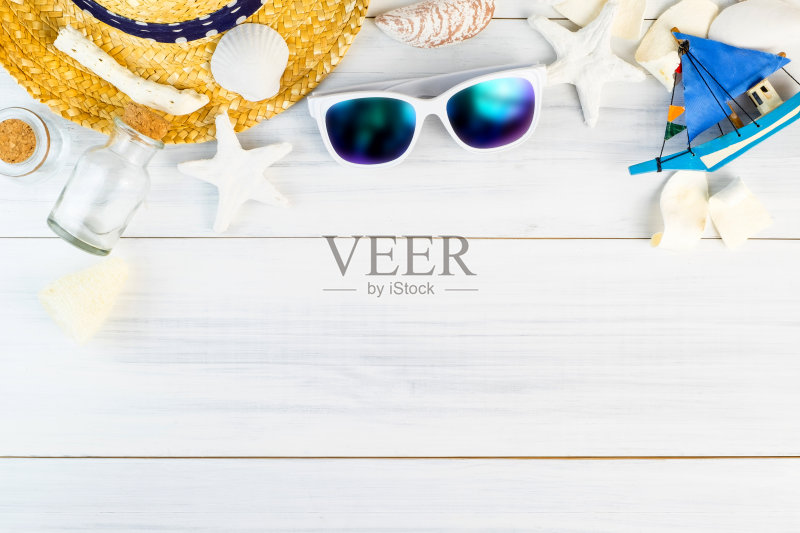 夏日沙滩配饰(白色太阳镜，海星，草帽，玻璃瓶，贝壳)上白色石膏木桌顶视图，夏日度假概念，留出空间添加文字。正版图片素材