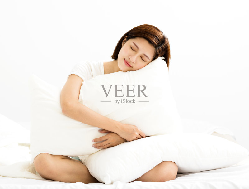 一个年轻女子在卧室里抱着一个枕头正版图片素材