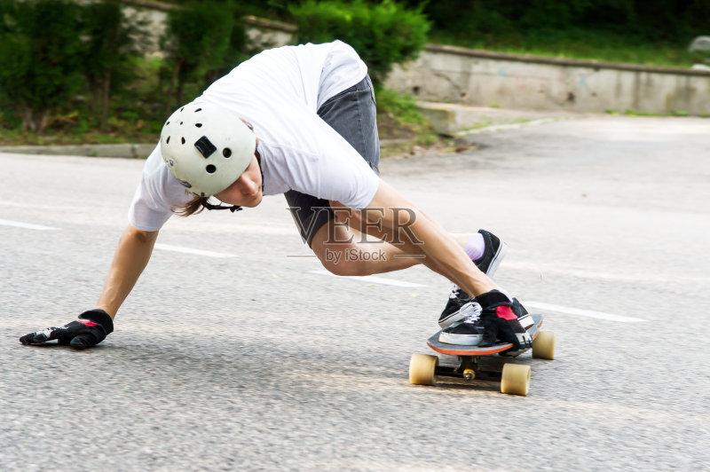 年轻人要在柏油路的长滑板上滑，带着火花滑正版图片素材