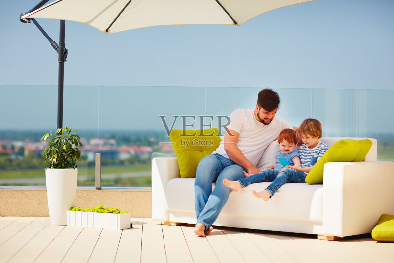 在温暖阳光明媚的日子里，一家人在屋顶露台上放松正版图片素材