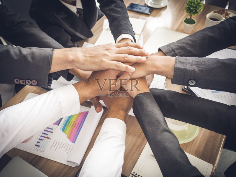 在办公室的会议桌/桌子上堆叠商人和女商人的手，团队合作，团结和商业合作的概念正版图片素材