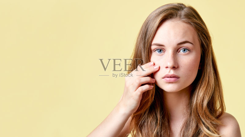 一个红发少年对着镜子看自己有问题。一个自卑的女孩在镜子前审视自己的皮肤。正版图片素材