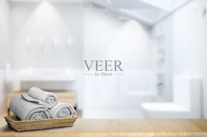 毛巾放在篮子里，放在木质台面上，模糊的浴室背景上有复印空间。用于产品展示蒙太奇。正版图片素材