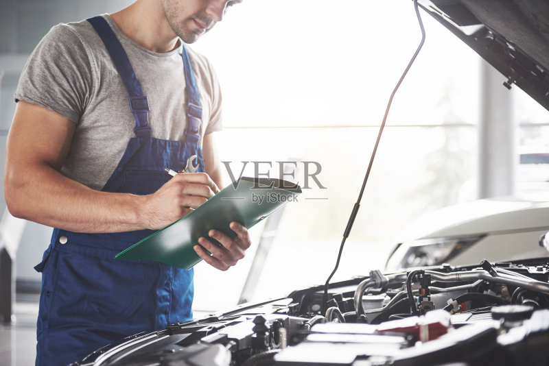 描绘了一个在他的车库工作的技工-汽车服务，维修，保养和人的概念正版图片素材