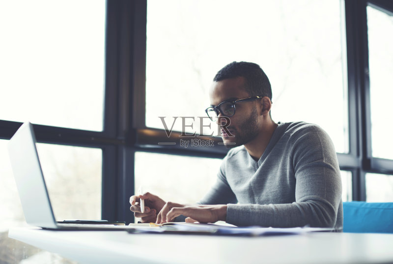 集中商户核算资料在网上数据库上，通过现代计算机连接到无线互联网连接。一名美国企业家在室内用笔记本电脑工作正版图片素材