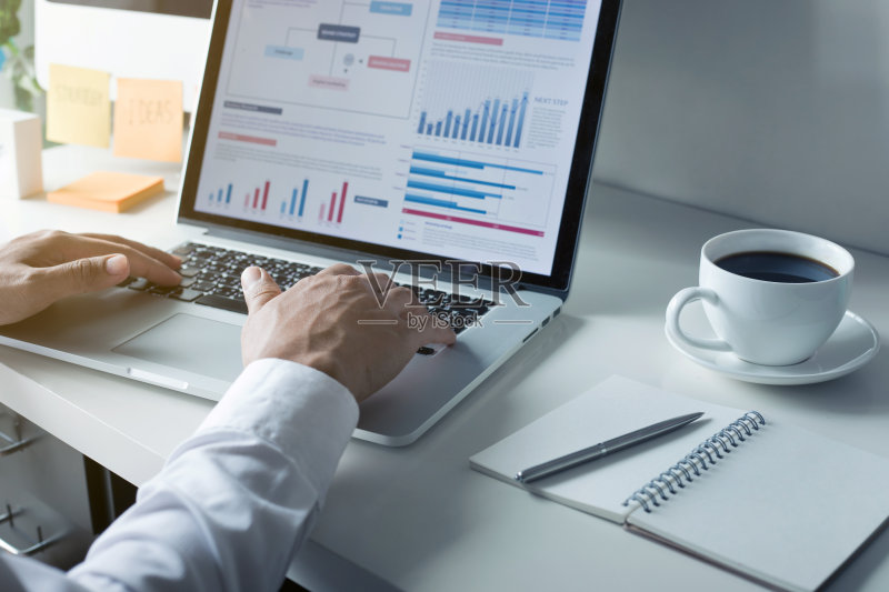 年轻的商人用图表在电脑上打字正版图片素材