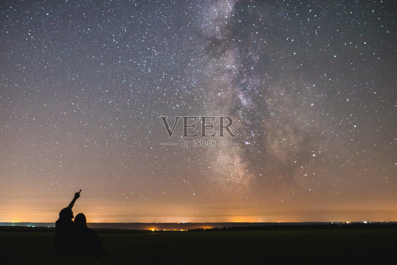 一对相爱的情侣在我们的家园银河系中心的星星下。两个人晚上在星空下正版图片素材