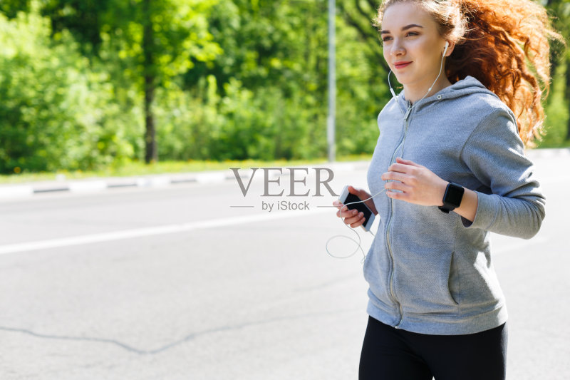 在户外慢跑时听音乐的女人正版图片素材