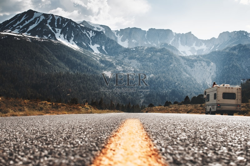 房车露营车站在路边，背景是一座大山。朋友们在山路上开车回家。游客们在路边休息，欣赏山景正版图片素材