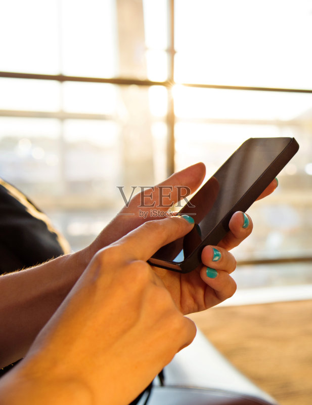 女人在机场手持智能手机正版图片素材