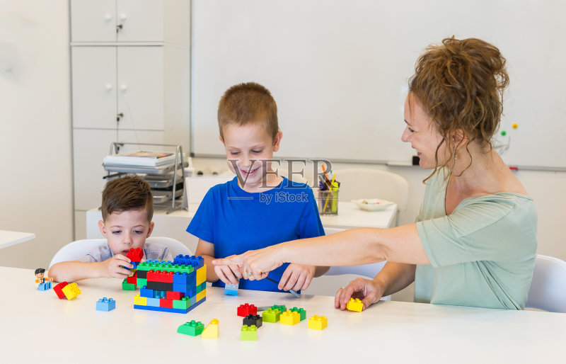 老师在幼儿园里和两个带着立方体的男孩玩正版图片素材