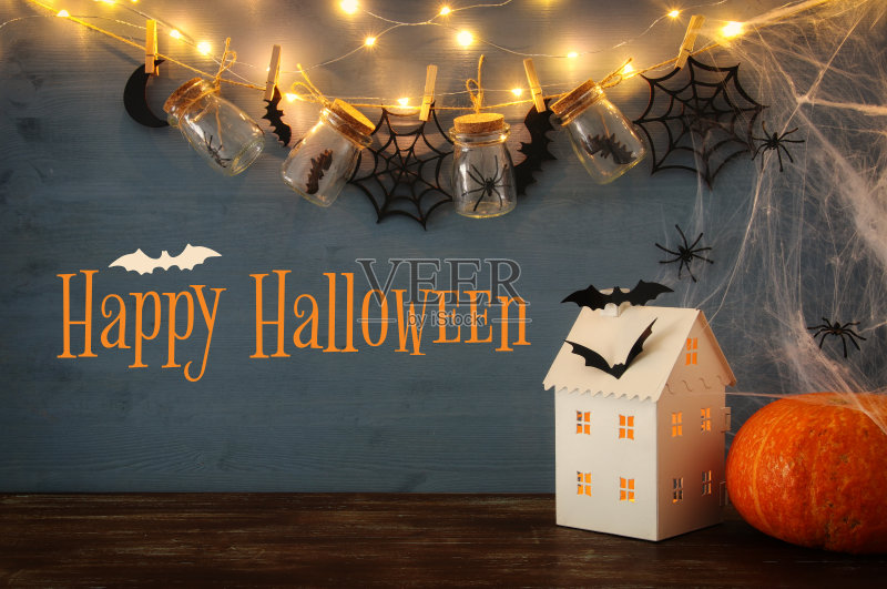 万圣节的节日的概念。神秘的房子里有灯光，前面是有蜘蛛的马尾石罐，浴室正版图片素材