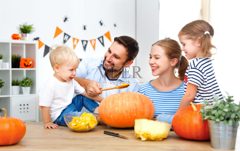 快乐的家庭妈妈爸爸和孩子们为万圣节切南瓜正版图片素材