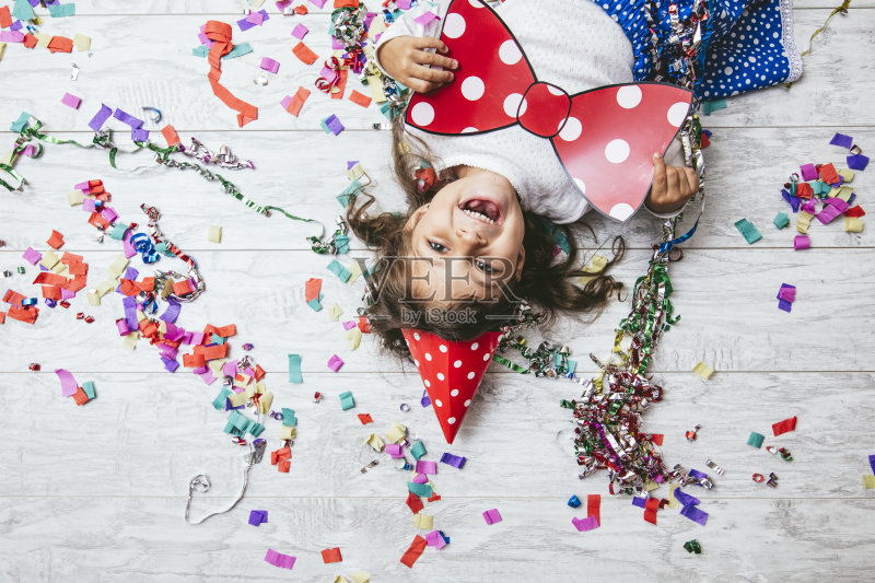 可爱的小女孩和美丽的五彩缤纷的地板和喜庆的帽子快乐的蝴蝶结正版图片素材