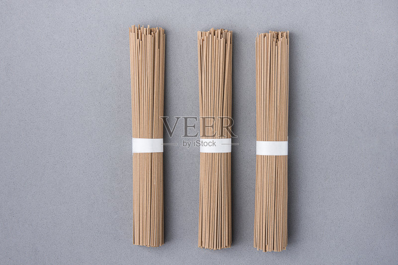 灰色背景上用白丝带绑成捆的薄荞麦面。日本料理除夕菜。干净简约的风格。平的。本空间正版图片素材