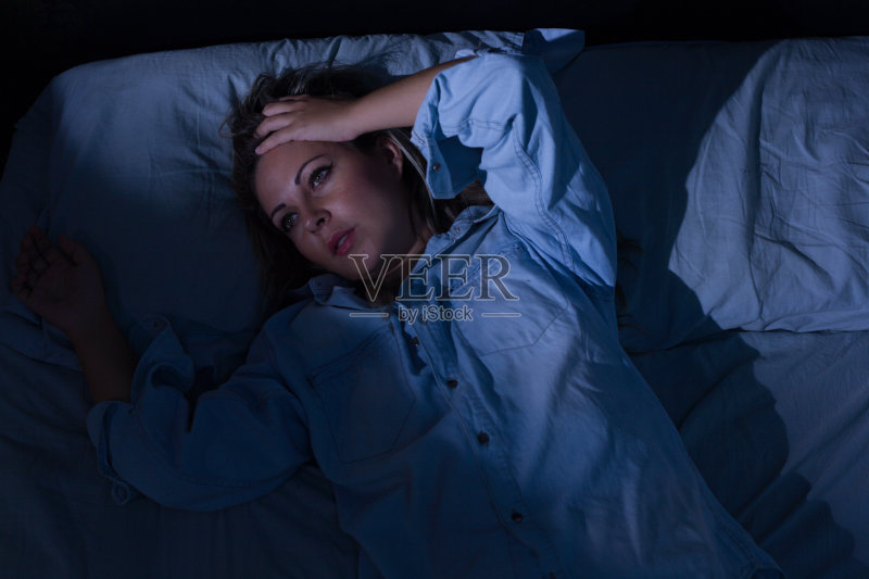 睡眠障碍、失眠。年轻的金发女人醒着躺在床上正版图片素材