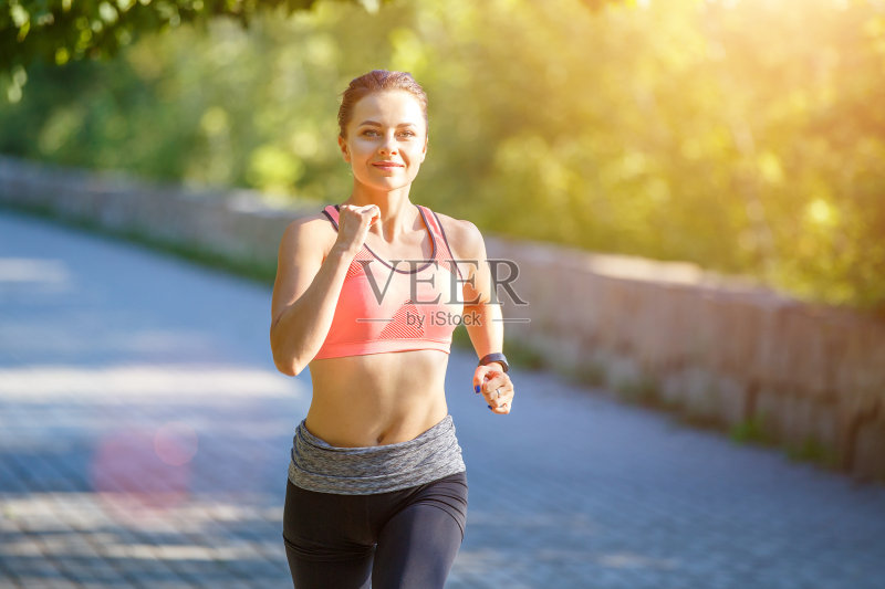 一个微笑的年轻女子早晨在公园里跑步正版图片素材