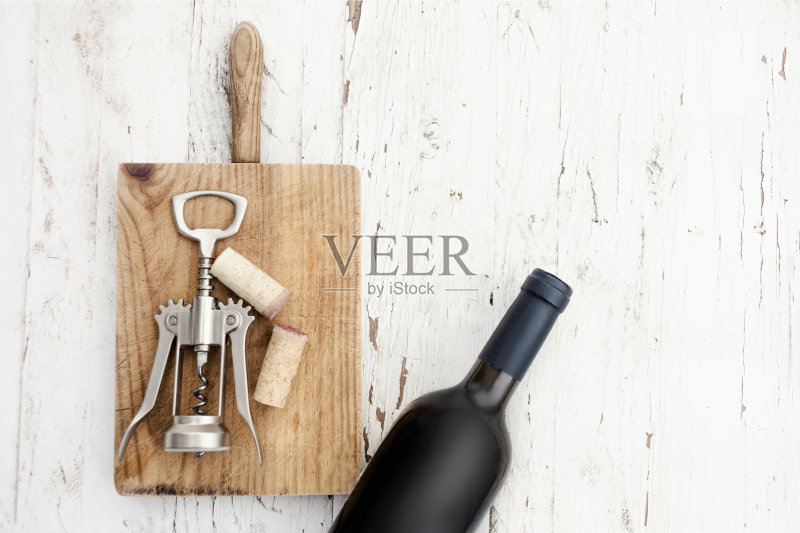 一瓶红酒，开瓶器和葡萄酒软木塞在质朴的白色木制背景，复制空间。品酒概念”n正版图片素材