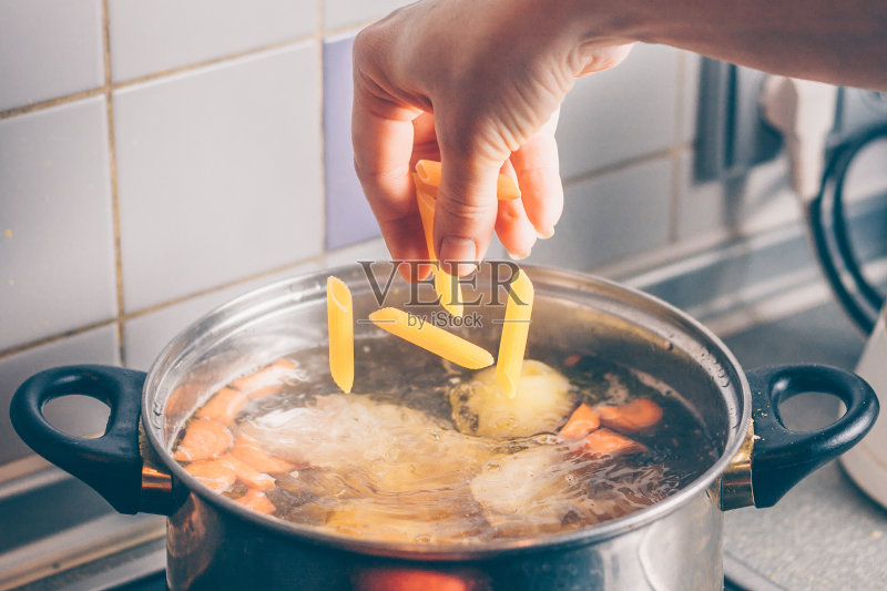 厨师把通心粉加到汤里正版图片素材