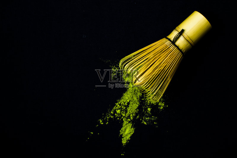 把竹打蛋器和抹茶绿茶粉放在黑色的背景上。正版图片素材