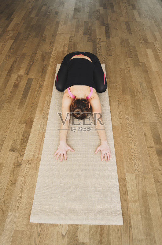 女人在室内的垫子上做瑜伽练习正版图片素材