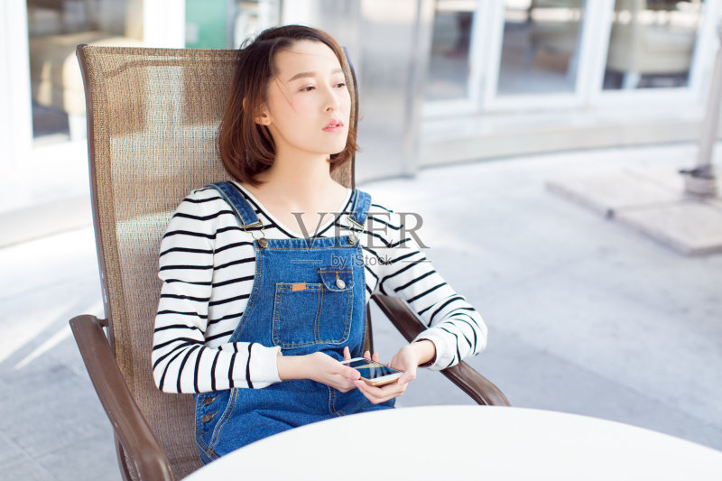 坐在路边餐厅用智能手机的女人正版图片素材