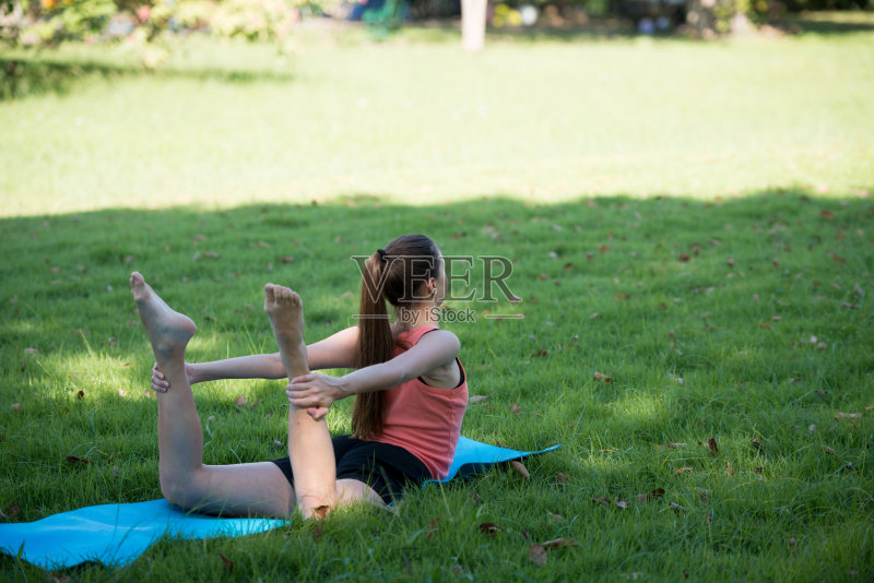 一个年轻女子在公园外面练瑜伽。健康的生活方式和放松的理念。正版图片素材