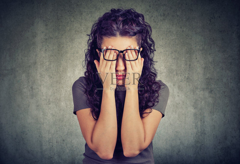 年轻女子戴着眼镜，双手遮住脸和眼睛正版图片素材