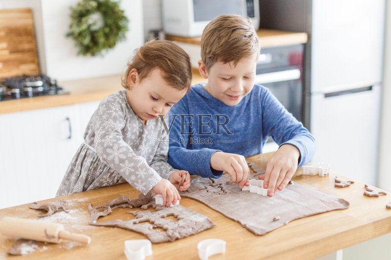 孩子们在家里厨房做圣诞饼干。家庭圣诞时间，兄弟姐妹正版图片素材