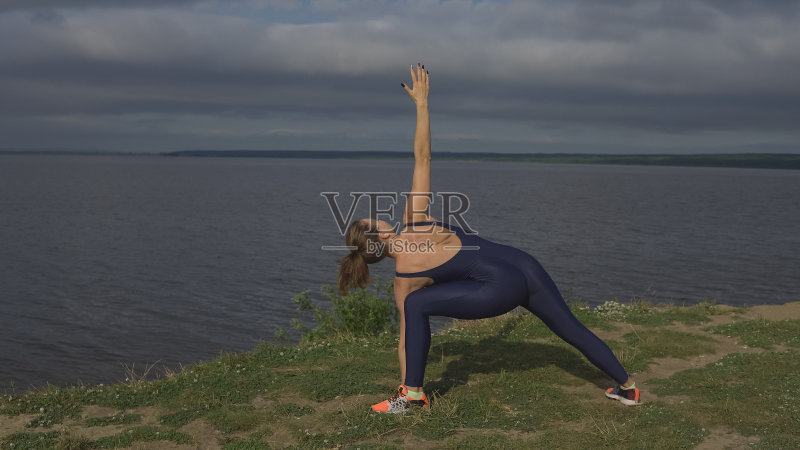 穿着蓝色运动服的女人，在户外练习瑜伽。正版图片素材