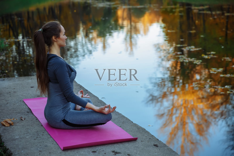 一位年轻女子在秋天的城市公园里做瑜伽练习。健康生活方式的概念正版图片素材