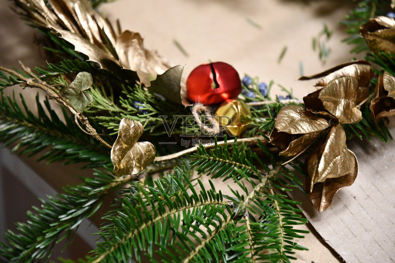 华丽的冬天花环的细节由针叶树的树枝和金色的树叶装饰红色和黄色的圣诞钟声。手工制作的花环特写镜头。新年装饰。正版图片素材