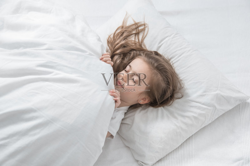 可爱的长头发小女孩睡在床上。正版图片素材
