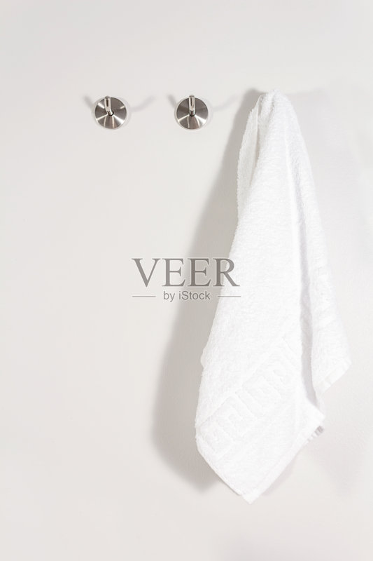 白色毛巾布毛巾挂在金属挂钩上。正版图片素材