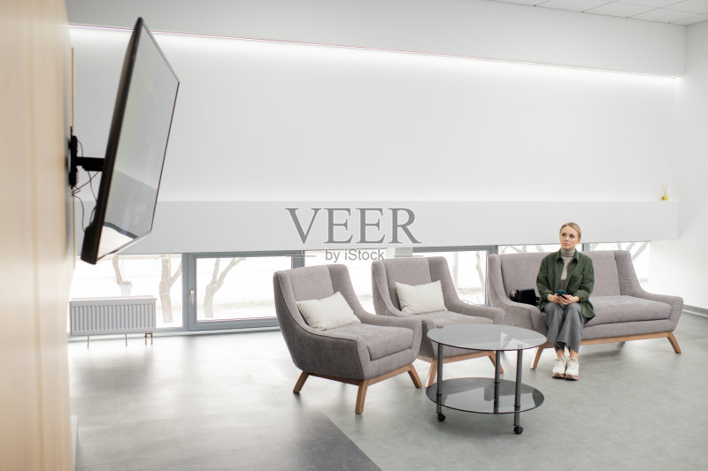 年轻随意的女人坐在沙发里当代医疗中心正版图片素材