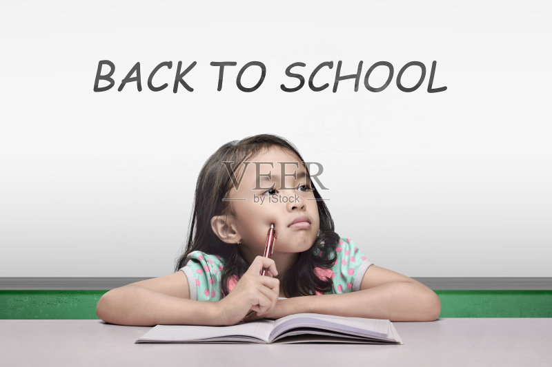 亚洲小女孩与笔和书思考的东西正版图片素材