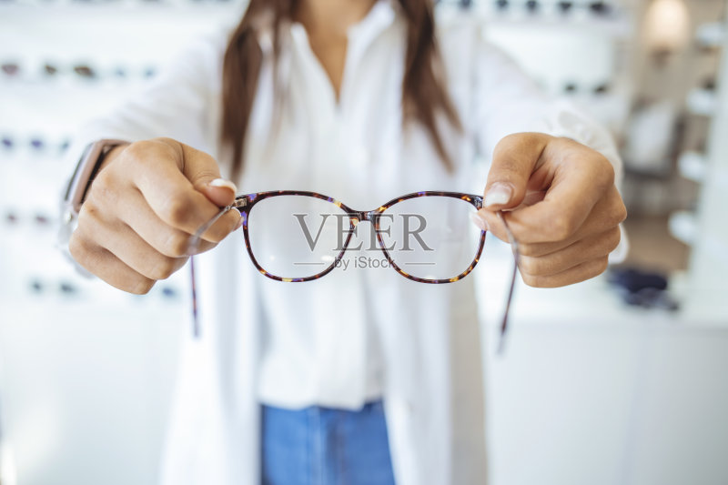 眼镜师在眼镜店展示并推荐眼镜正版图片素材