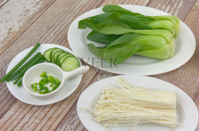 桌上摆着各种食材，小白菜、葱花、金针菇和黄瓜片。素食者的概念正版图片素材